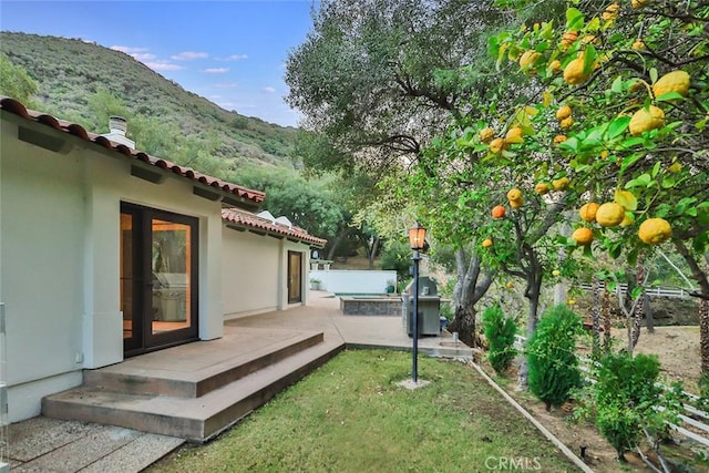 view of yard featuring a patio area, an outdoor hot tub, a mountain view, and fence