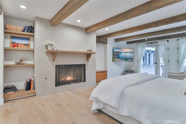 bedroom with access to exterior, recessed lighting, wood finished floors, beamed ceiling, and a lit fireplace