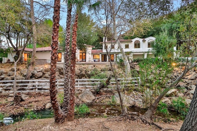 mediterranean / spanish home with fence, a tiled roof, and stucco siding