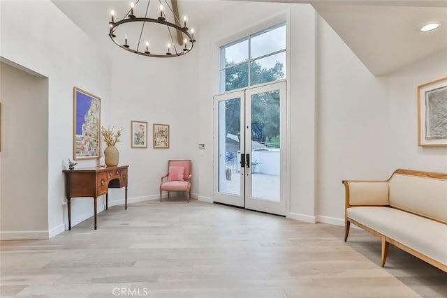 living area with french doors, light wood-type flooring, and baseboards