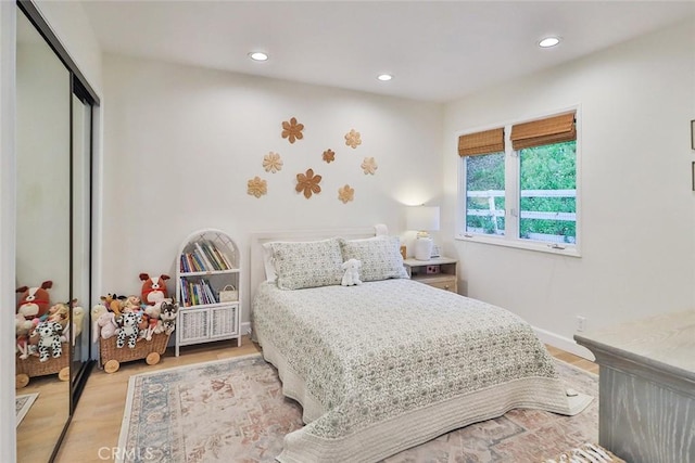 bedroom featuring light wood finished floors, baseboards, a closet, and recessed lighting