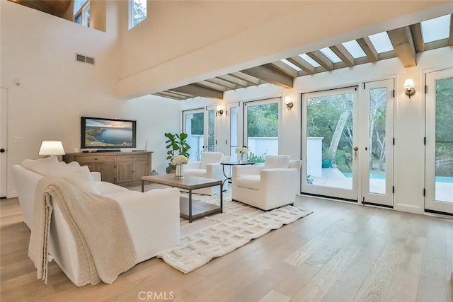 interior space with a high ceiling, visible vents, beamed ceiling, and wood finished floors