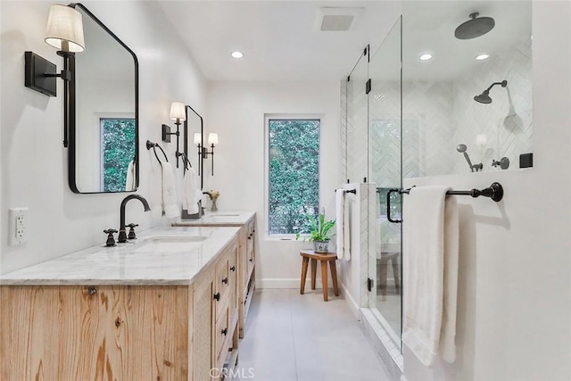 full bathroom featuring double vanity, plenty of natural light, a shower stall, and a sink