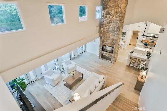 living area with a towering ceiling, light wood-type flooring, and a fireplace