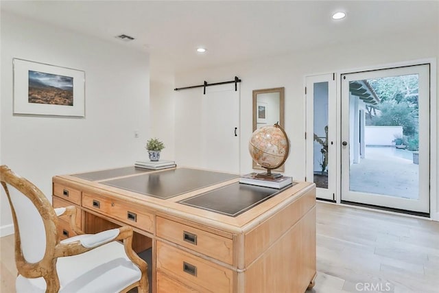 home office featuring a barn door, light wood-style floors, visible vents, and recessed lighting