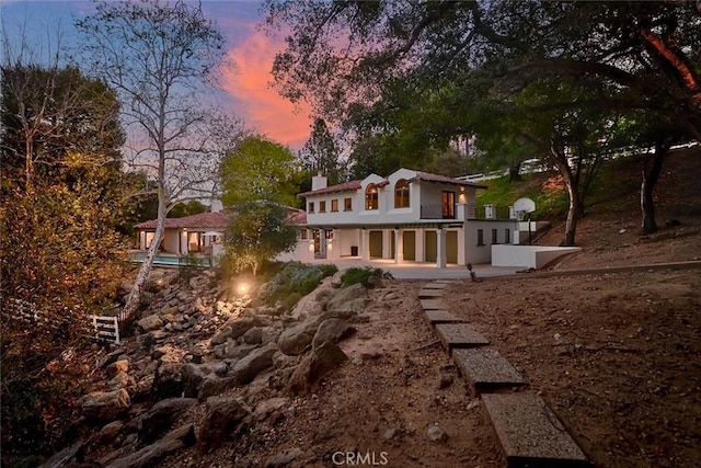 back of property at dusk with a patio and a chimney