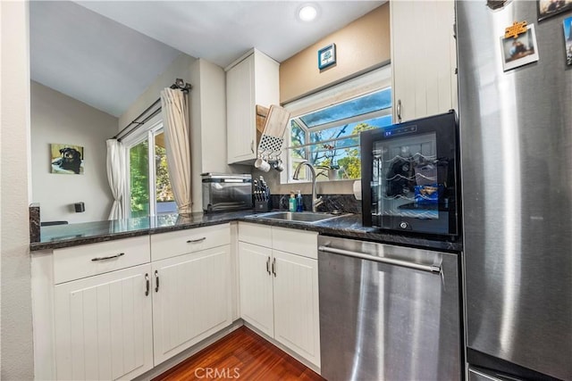 kitchen with a toaster, appliances with stainless steel finishes, dark wood-type flooring, a sink, and vaulted ceiling