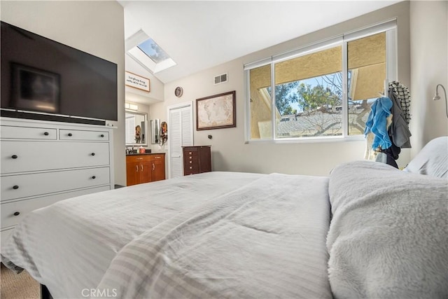 bedroom featuring lofted ceiling with skylight, a closet, and visible vents