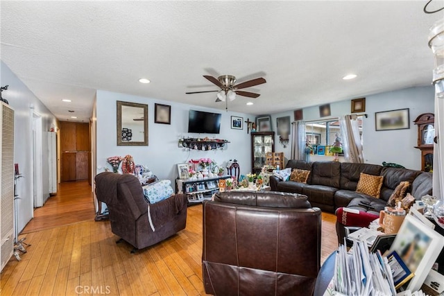 living room featuring light wood-style flooring, recessed lighting, a ceiling fan, and a textured ceiling