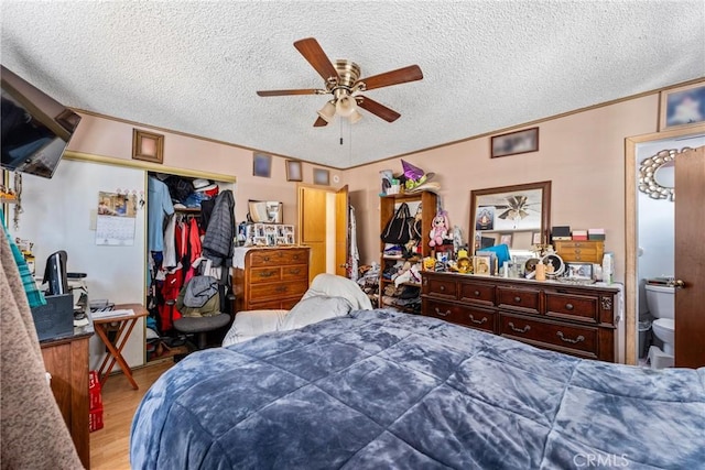 bedroom with a ceiling fan, wood finished floors, a closet, a textured ceiling, and crown molding