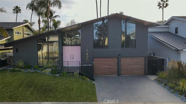 view of front of home with a garage, decorative driveway, and a front yard