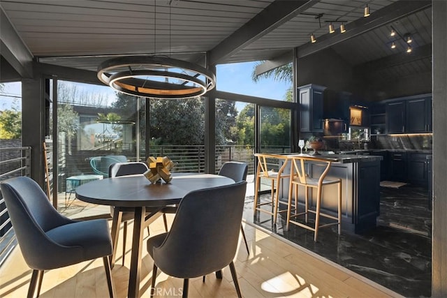 sunroom featuring lofted ceiling with beams, rail lighting, and plenty of natural light