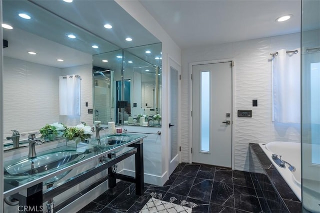 bathroom featuring a washtub, a shower with door, a sink, and double vanity