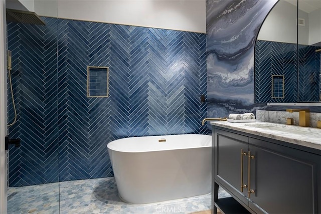 bathroom with a freestanding tub, tile walls, tiled shower, and vanity