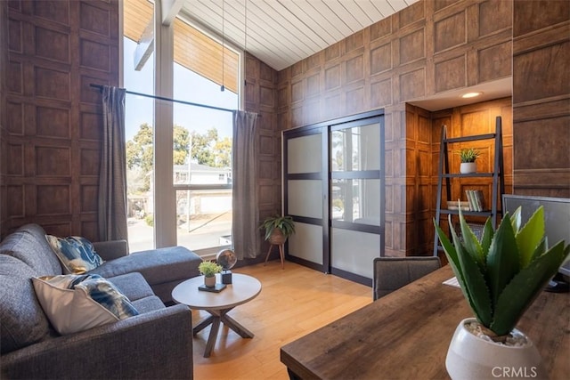 living room featuring high vaulted ceiling, wooden ceiling, wooden walls, a decorative wall, and wood finished floors