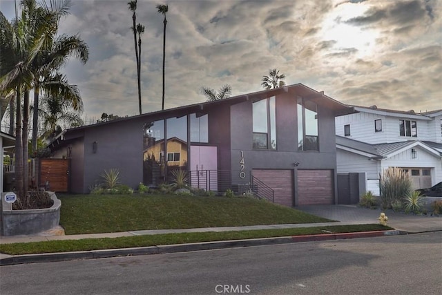 view of front facade with a front yard, driveway, an attached garage, and stucco siding