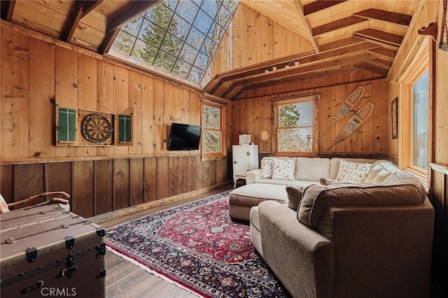 living area with high vaulted ceiling, wood walls, and wood finished floors