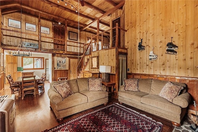 living area with wooden ceiling, wood-type flooring, stairway, wood walls, and beam ceiling