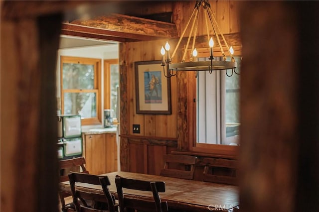 dining area with a chandelier and wooden walls