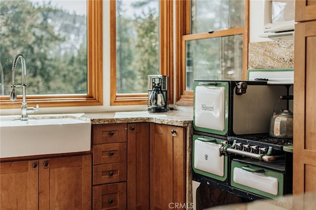 kitchen featuring light countertops, brown cabinetry, and a sink