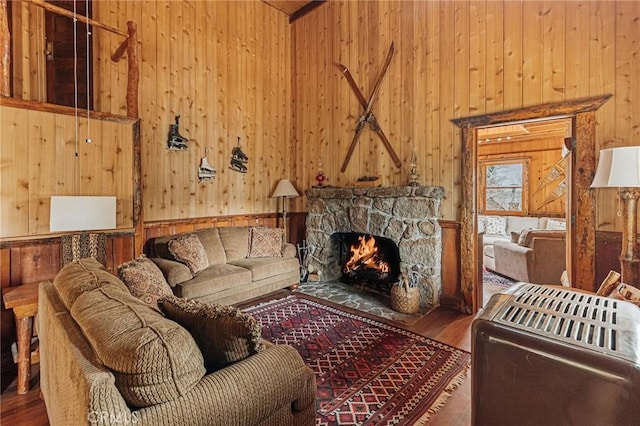 living room featuring a fireplace, wooden walls, a towering ceiling, and wood finished floors