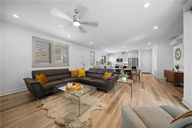 living room featuring recessed lighting, baseboards, a wall mounted air conditioner, and light wood finished floors
