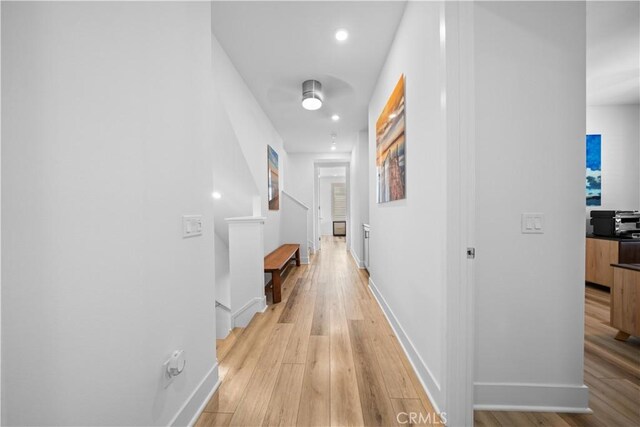 corridor featuring light wood-type flooring and baseboards