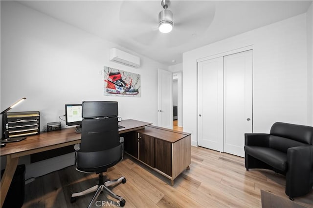 office space with light wood-style flooring, ceiling fan, and an AC wall unit