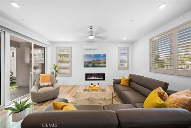 living area with a glass covered fireplace, baseboards, recessed lighting, and wood finished floors