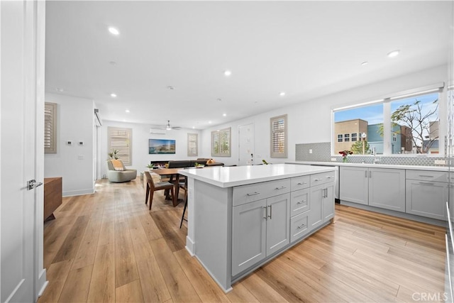 kitchen with recessed lighting, a center island, light wood-style flooring, and gray cabinetry