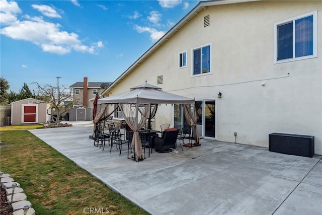 back of property featuring stucco siding, a patio, a shed, a gazebo, and an outdoor structure