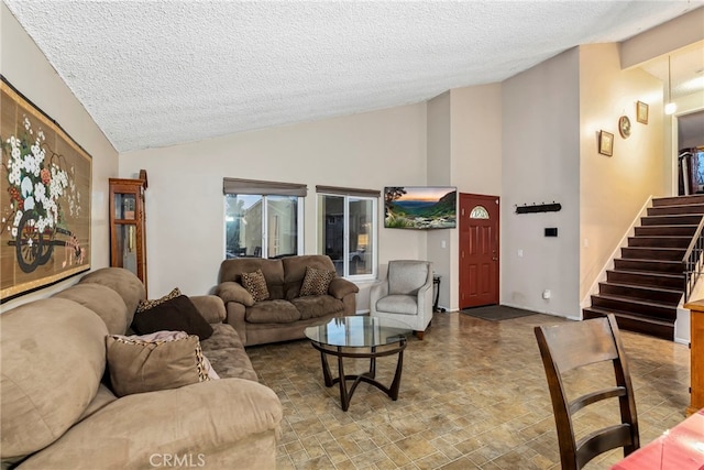 living area featuring stairway, a textured ceiling, and vaulted ceiling