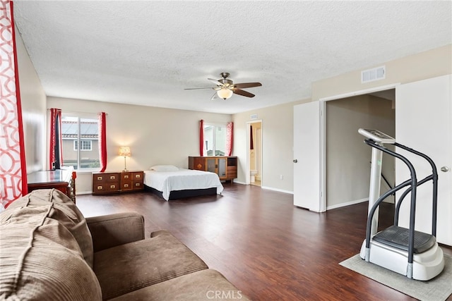 bedroom with baseboards, wood finished floors, visible vents, and a textured ceiling