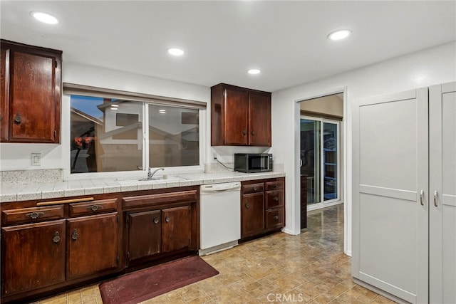 kitchen with a sink, recessed lighting, light countertops, and white dishwasher