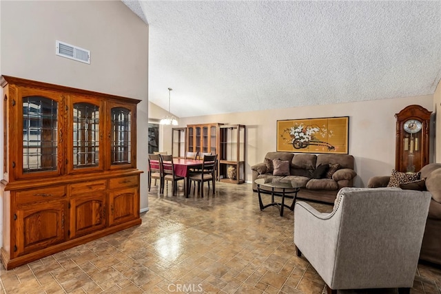 living area featuring lofted ceiling, visible vents, and a textured ceiling