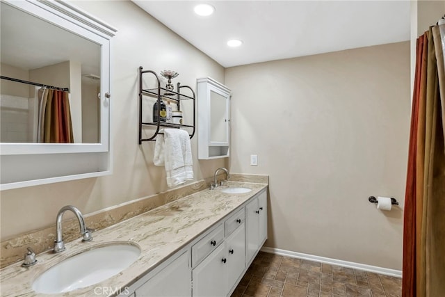 bathroom featuring double vanity, recessed lighting, baseboards, and a sink