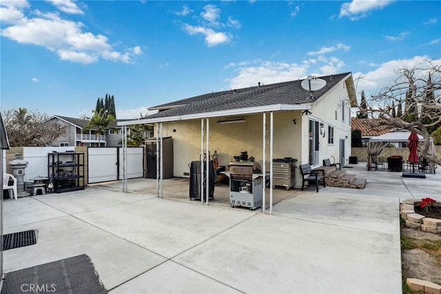 back of property with stucco siding, a gate, a patio, fence, and a gazebo