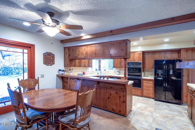 kitchen with decorative backsplash, brown cabinets, a peninsula, a textured ceiling, and black appliances