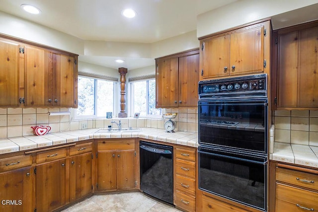 kitchen featuring black appliances, brown cabinetry, a sink, and decorative backsplash