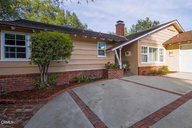 exterior space with a garage, brick siding, and a chimney