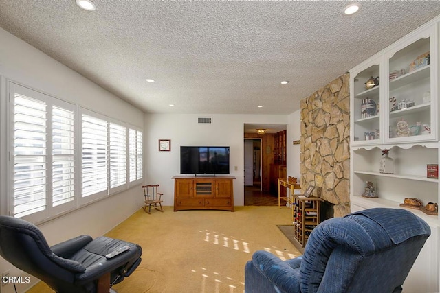 carpeted living area featuring a textured ceiling, built in shelves, visible vents, and recessed lighting