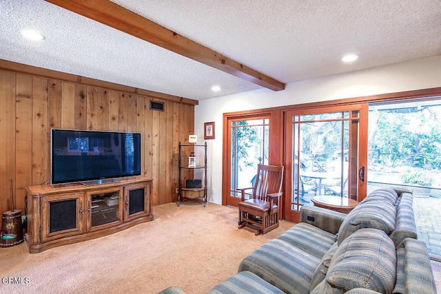 carpeted living room featuring wooden walls, visible vents, a textured ceiling, beam ceiling, and recessed lighting