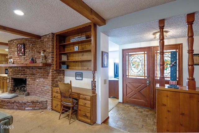 office featuring built in desk, beam ceiling, a fireplace, and a textured ceiling