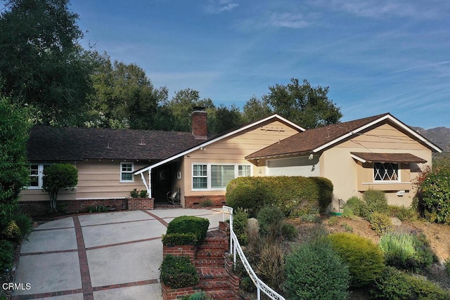 ranch-style house featuring a shingled roof and a chimney