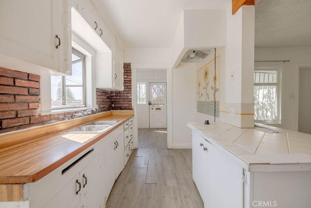 kitchen featuring a sink, light wood-style floors, white cabinets, and a textured ceiling