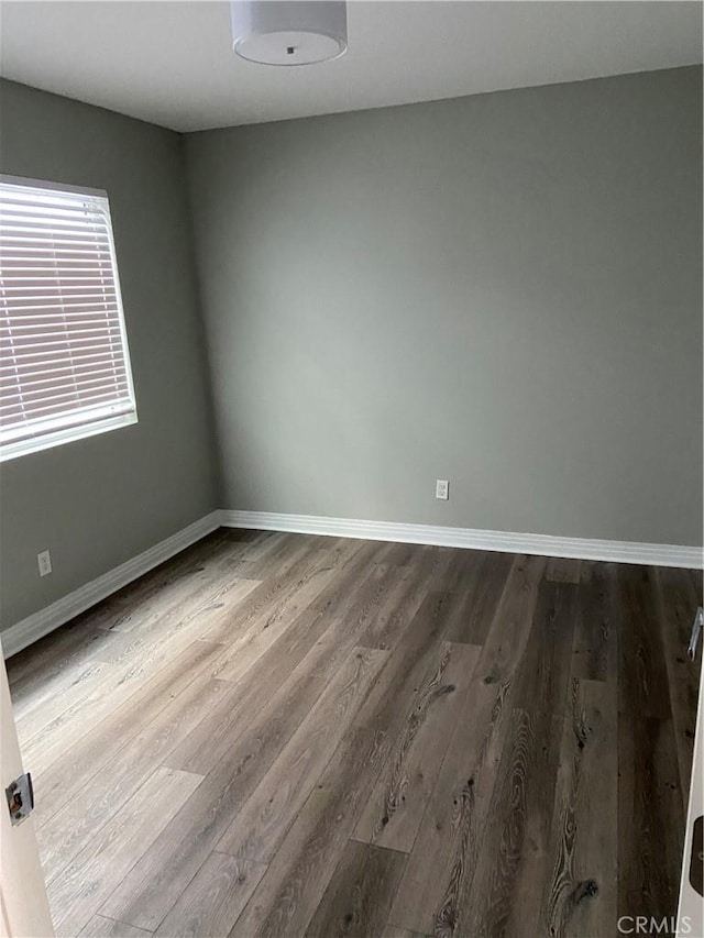 unfurnished room with baseboards and wood finished floors