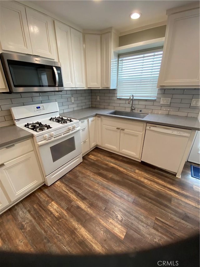 kitchen with white appliances, backsplash, dark wood-style flooring, and a sink