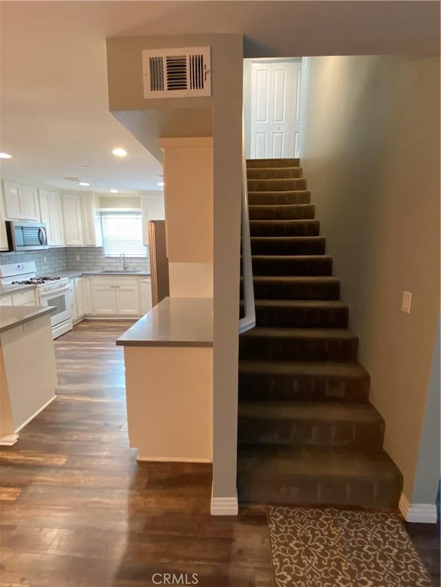 stairs with recessed lighting, visible vents, baseboards, and wood finished floors