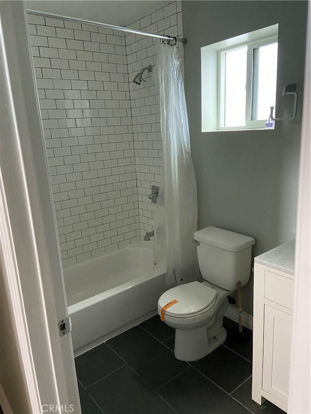 full bathroom featuring toilet, vanity, baseboards, tile patterned floors, and shower / bath combo