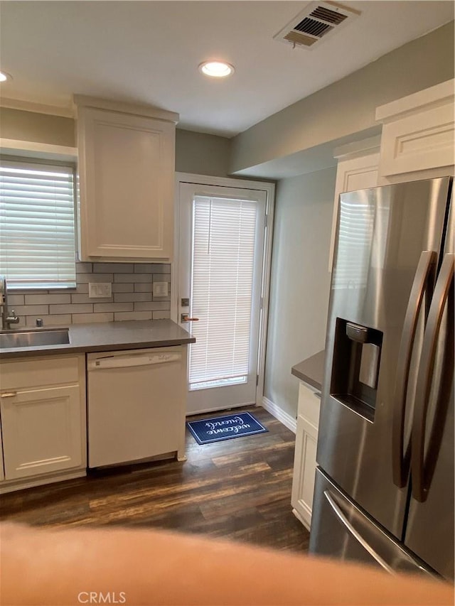 kitchen featuring visible vents, dark wood-style flooring, white dishwasher, stainless steel refrigerator with ice dispenser, and a sink